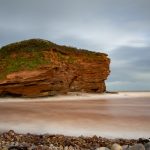 Budleigh Salterton roter Fels im Meer mit fluffigen Wellen durch Einsatz eines Graufilters