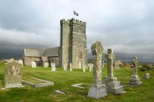 Tintagel Kirche mit Friedhof mit keltischen Kreuzen im Abendlicht und kornischer Flagge als Beispiel für ein Fotomotiv auf der Fotowanderreise Cornwalls Nordenit