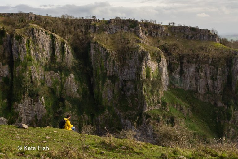 Winziger Mensch in gelber Jacke im Bild vor Cheddar Gorge Felsen als Größenvergleich für Tiefe in Landschaftsfotos