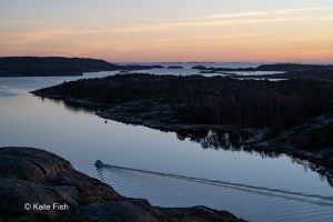 Ausfahrendes Boot bei Sonnenuntergang aus dem Hafen von Grebbestad an der Westküste Schwedens alles nur als Silhouette im Gegenlicht