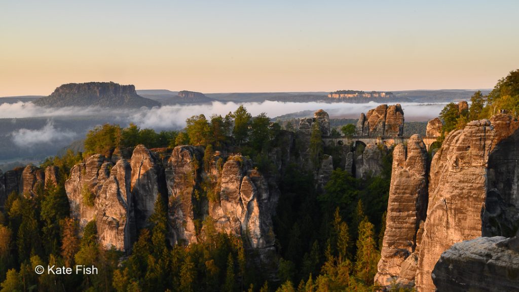 Wenn man sich Zeit nimmt beim in der sächsische Schweiz wandern und Bastei im Sonnenaufgang fotografieren. Dann kommt ein Foto mit der Basteibrücke und in Nebelfelder eingebettete Festung Königstein heraus.