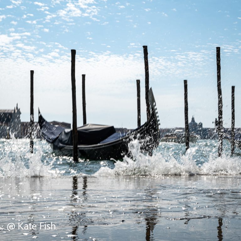 Gondeln in Venedig fotografieren geht bei Hochwasser mit schönem Spritzwasser im Vordergrund